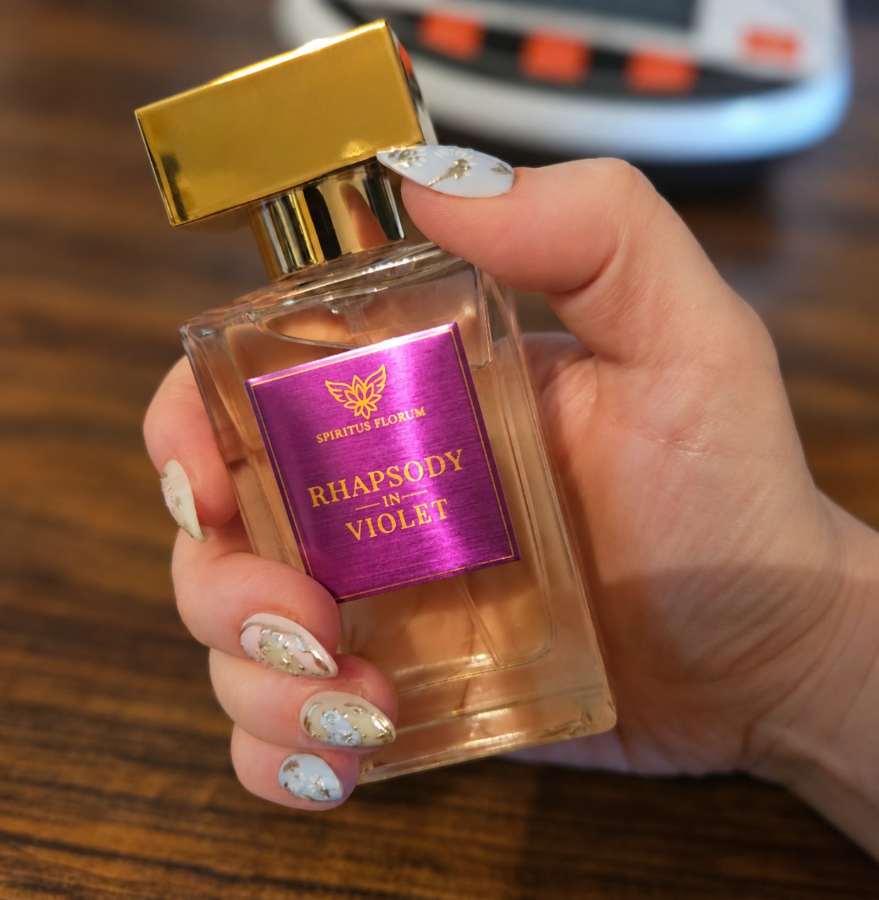A bottle of Rhapsody in Violet held in Clare’s hand, with digital scales behind